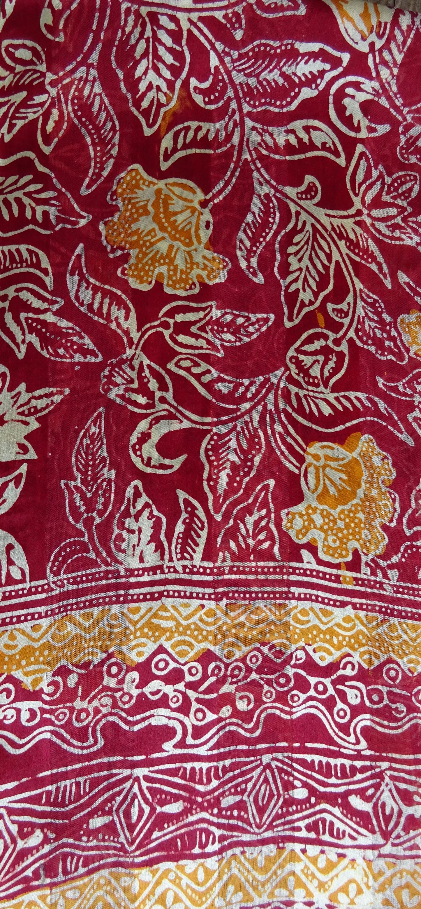 Handgefertigter Seidenschal in Dunkelrot mit Cognac und weißem floralem Muster, gebatikt, zarte dunkelrote Fransen, Maße ca. 180 x 52 cm.