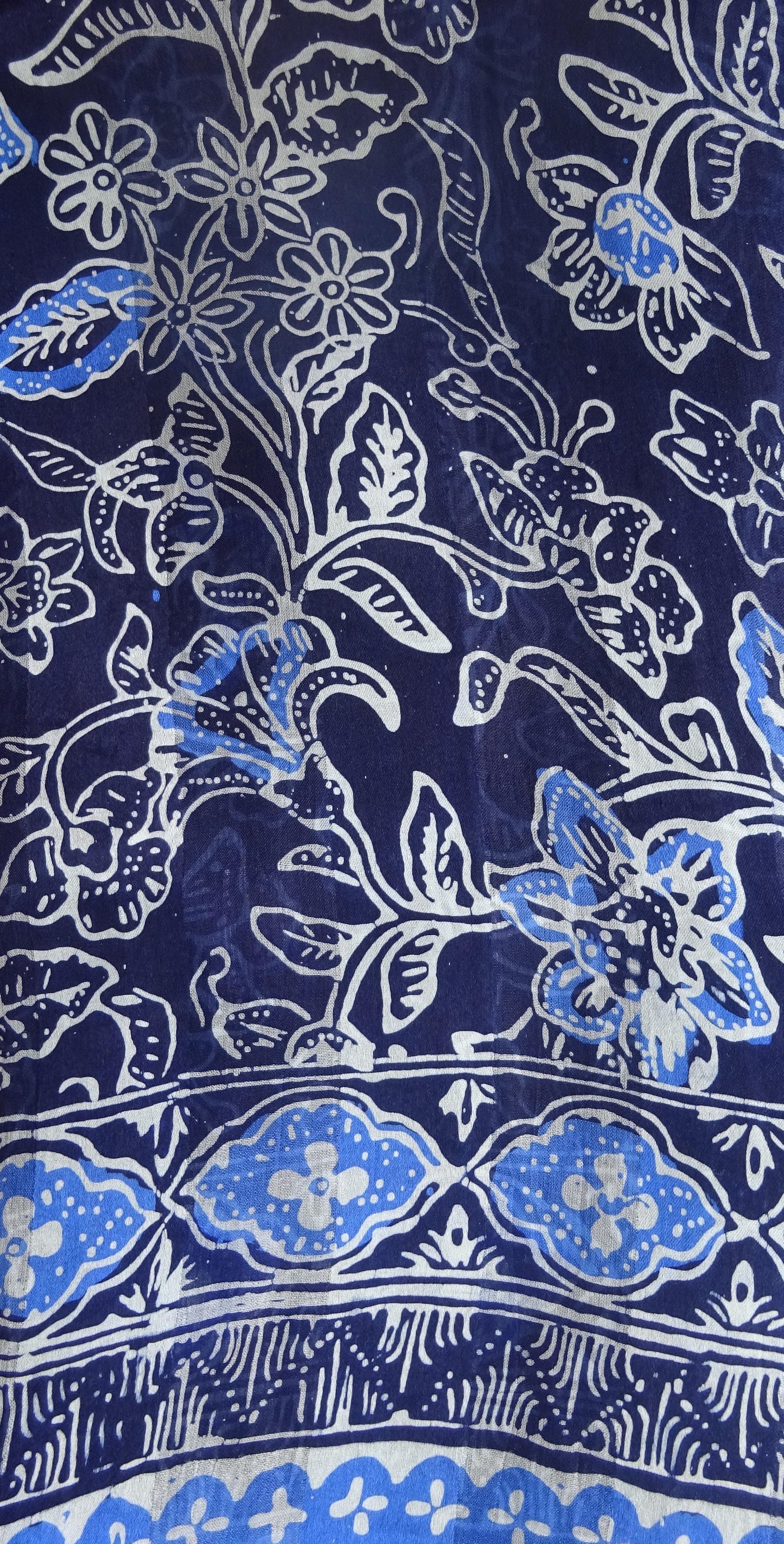Handgebatikter Seidenschal in Dunkelblau mit leuchtend blauem und weißem floralem Muster, zarte dunkelblaue Fransen, leicht fließende Seide, 180 x 52 cm.