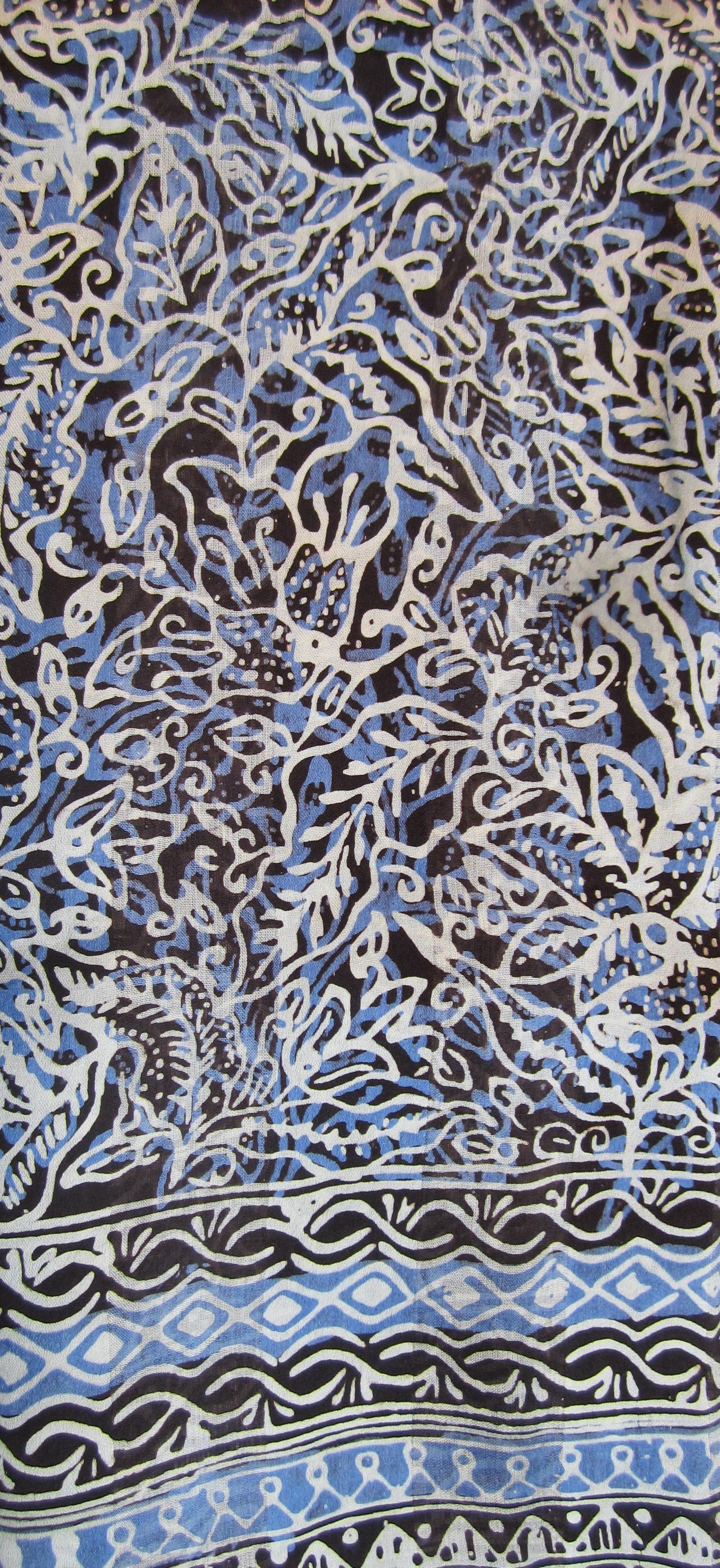 Handgebatikter Seidenschal in Blau mit Weiß und Schwarz, florales Muster, zarte blaue Fransen, 180 x 52 cm.