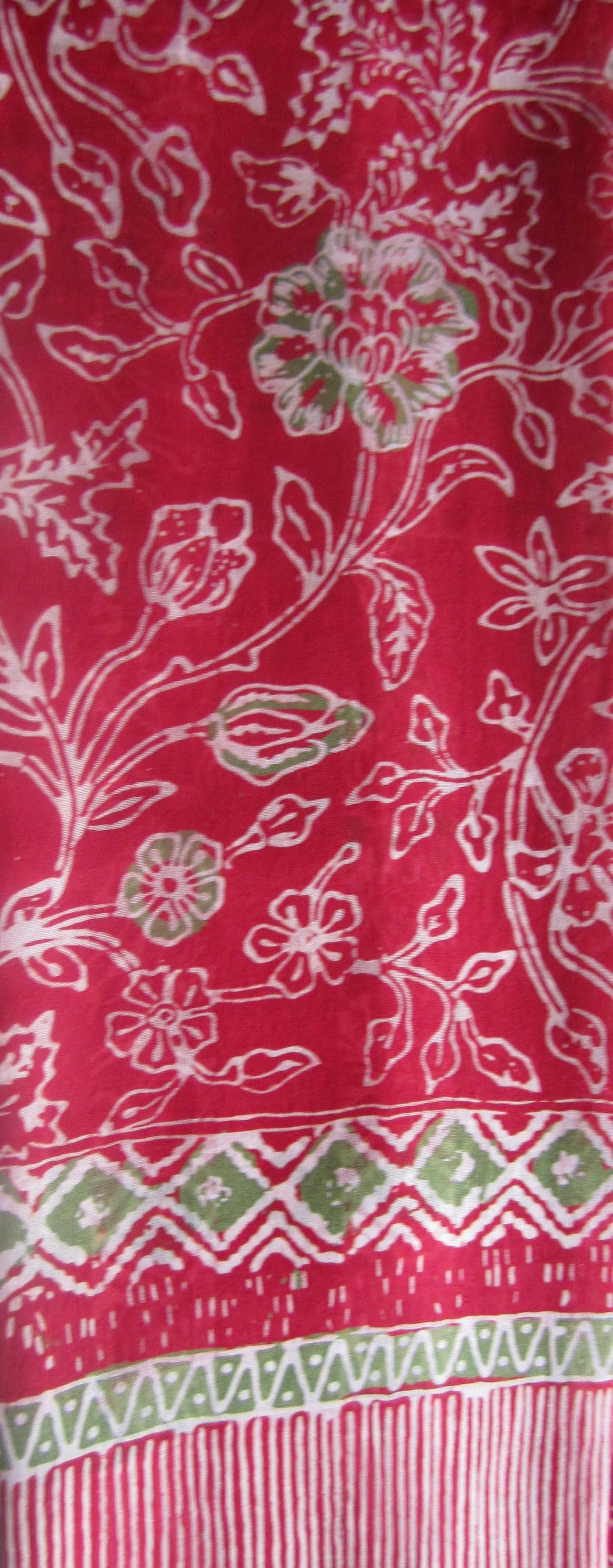Zartfließender gebatikter Seidenschal mit floralem Muster in Rot, Grün und Weiß, handgefertigt mit feinen Fransen, ca. 180 x 52 cm.
