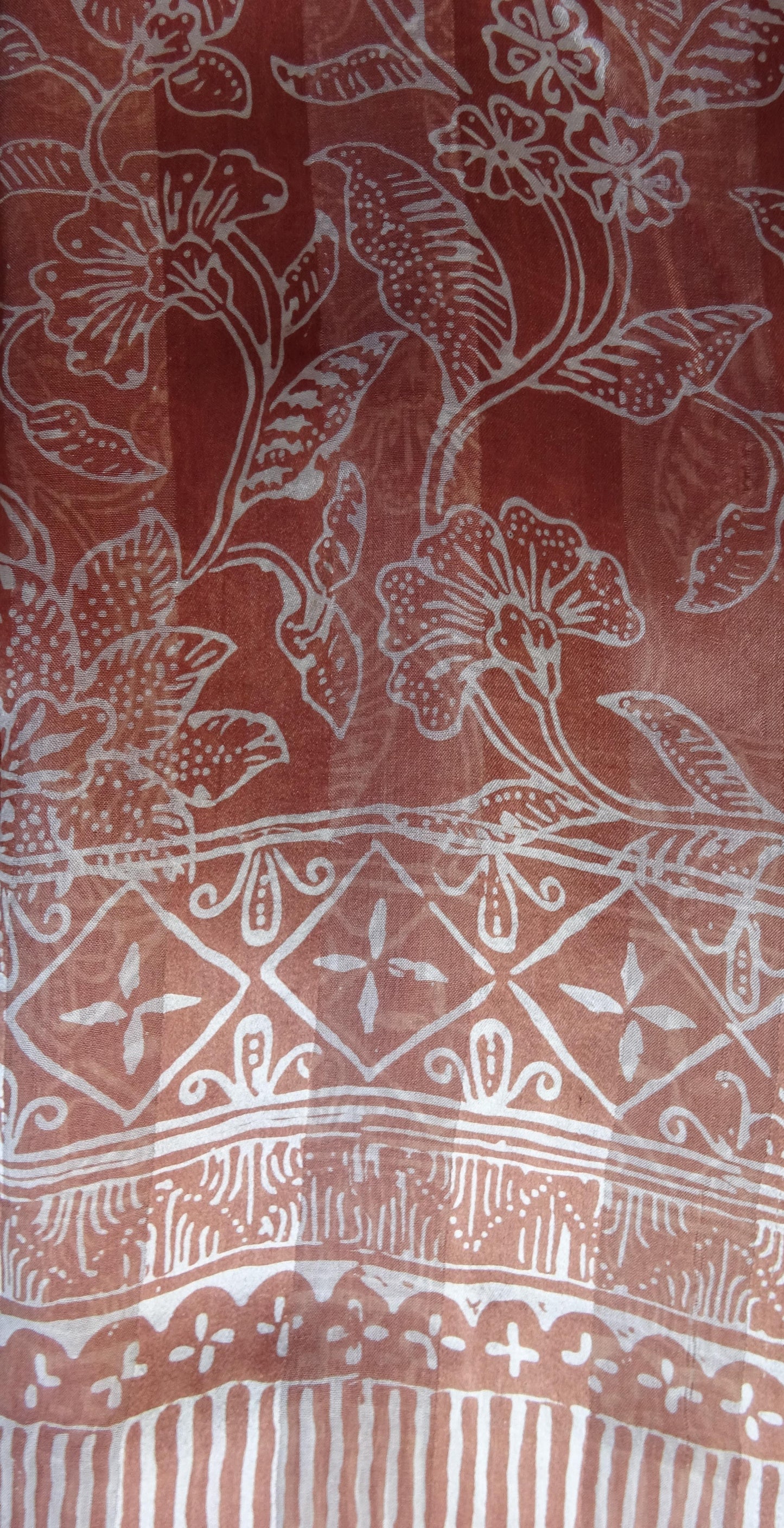 Handgefertigter Seidenschal in Mittelbraun mit floralem Muster, gebatikt, zarte hellbraune Fransen, Maße ca. 180 x 52 cm.